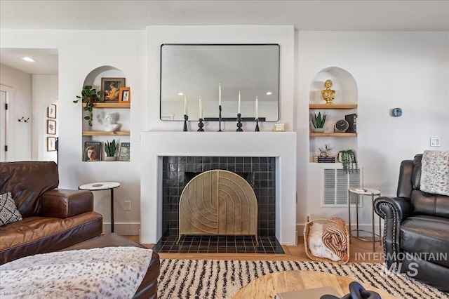 interior space featuring a tiled fireplace, dark hardwood / wood-style flooring, and built in shelves