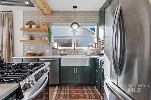 kitchen with sink, green cabinetry, pendant lighting, stainless steel appliances, and backsplash