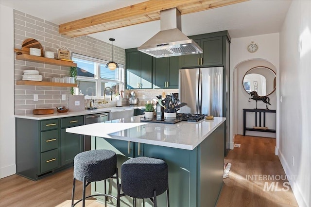 kitchen with appliances with stainless steel finishes, a breakfast bar area, island range hood, and green cabinetry