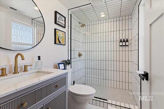 bathroom featuring vanity, toilet, and a tile shower