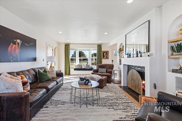 living room with hardwood / wood-style flooring, a fireplace, and built in shelves