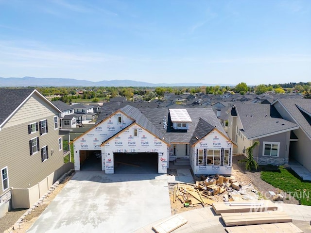 unfinished property featuring concrete driveway, a residential view, an attached garage, and a mountain view