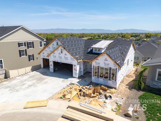 unfinished property featuring an attached garage, a mountain view, and driveway