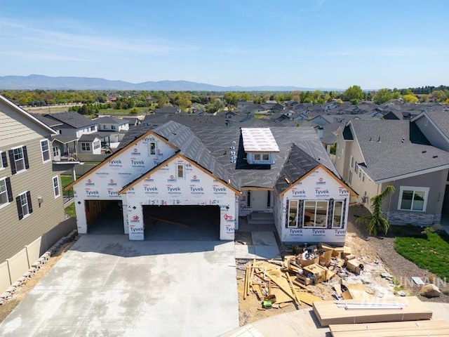 unfinished property featuring concrete driveway, a residential view, a mountain view, and an attached garage
