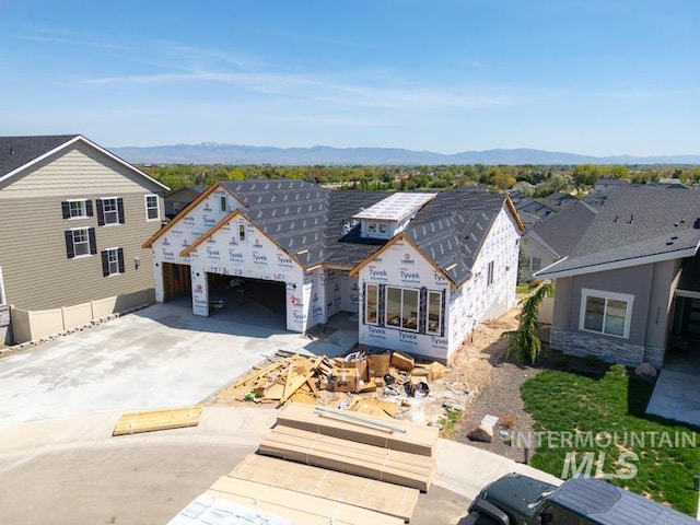 property in mid-construction featuring a mountain view, concrete driveway, an attached garage, and stone siding