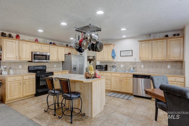 kitchen with sink, light brown cabinets, light tile patterned flooring, and stainless steel appliances