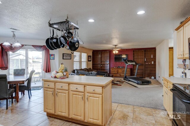 kitchen featuring ceiling fan, light brown cabinets, hanging light fixtures, a textured ceiling, and light carpet