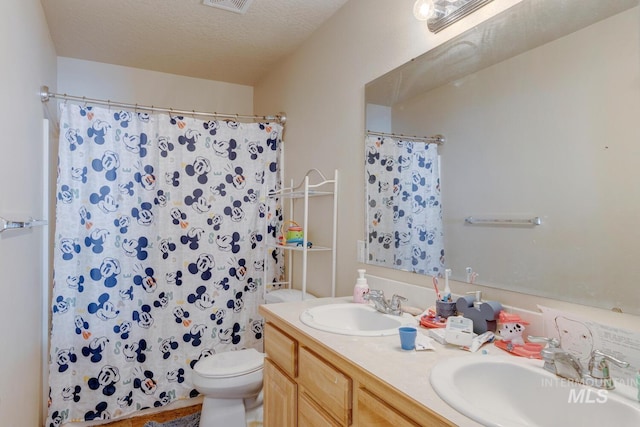 bathroom with a shower with curtain, vanity, toilet, and a textured ceiling