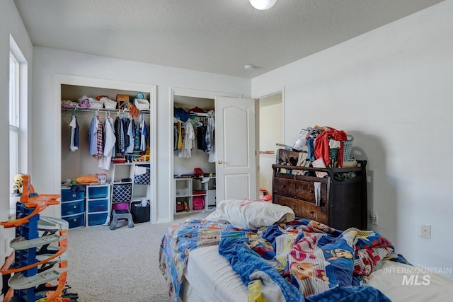 carpeted bedroom featuring multiple closets and a textured ceiling