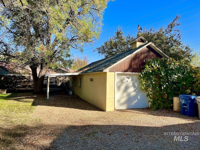 view of side of property with a carport, a garage, and an outdoor structure