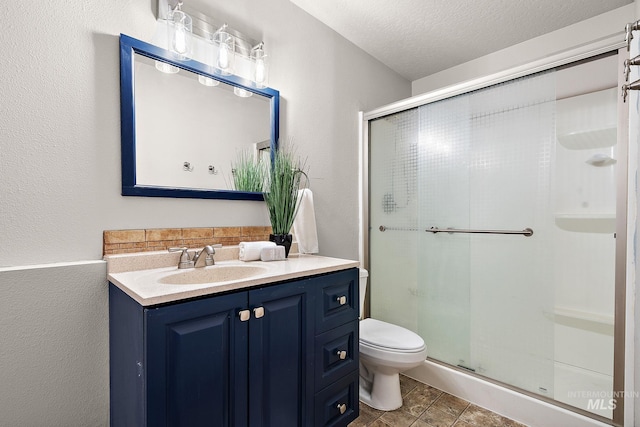 full bathroom with a stall shower, a textured wall, toilet, a textured ceiling, and vanity