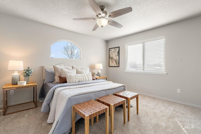 bedroom featuring ceiling fan, baseboards, a textured ceiling, and light colored carpet