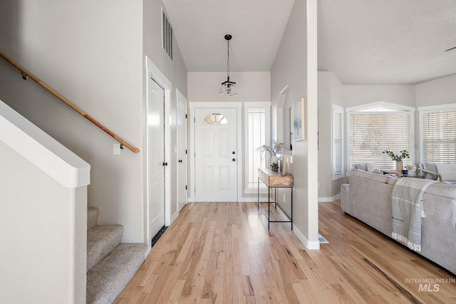 entryway featuring visible vents, light wood-style flooring, stairway, a textured ceiling, and baseboards