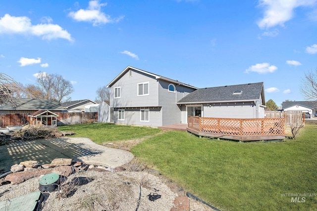 rear view of property featuring a fenced backyard, a deck, and a lawn