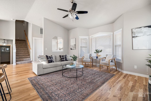 living room with vaulted ceiling, visible vents, stairs, and light wood-style flooring