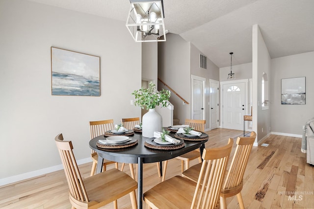 dining space featuring lofted ceiling, visible vents, an inviting chandelier, light wood-type flooring, and baseboards