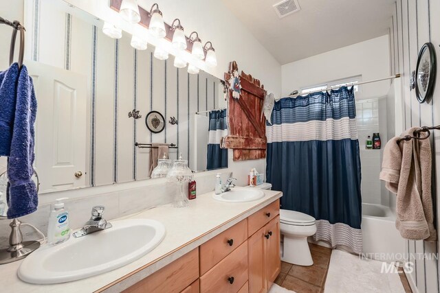 bathroom with double vanity, toilet, visible vents, and a sink