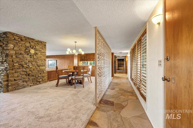 2401 Terrace Dr, Caldwell, ID 83605 - corridor with a textured ceiling, a chandelier, carpet floors, and stone flooring
