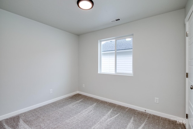 carpeted spare room with visible vents and baseboards