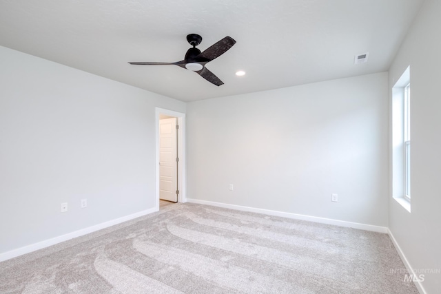 unfurnished room with light colored carpet, baseboards, a ceiling fan, and visible vents