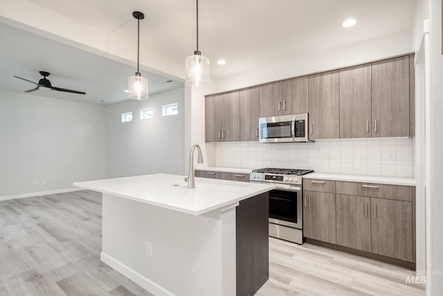 kitchen with tasteful backsplash, appliances with stainless steel finishes, light countertops, modern cabinets, and light wood-style floors