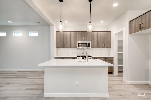 kitchen featuring light countertops, decorative backsplash, stainless steel microwave, and modern cabinets