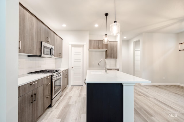 kitchen featuring a sink, modern cabinets, backsplash, light countertops, and appliances with stainless steel finishes