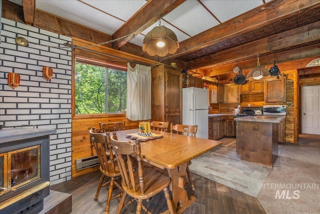 dining area with beamed ceiling, wooden walls, a baseboard radiator, and dark wood finished floors