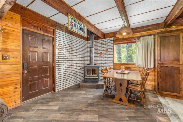 dining area with a wood stove, wood finished floors, and wooden walls