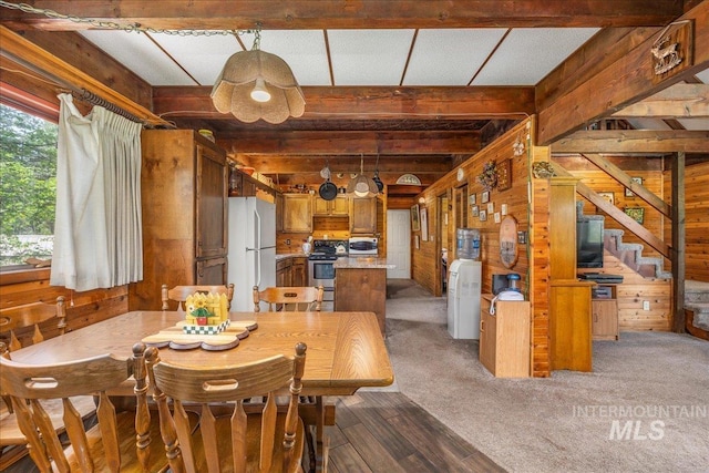 dining room with wood finished floors, beam ceiling, and wood walls
