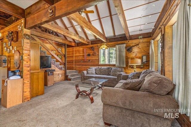 carpeted living room with lofted ceiling with beams and wood walls