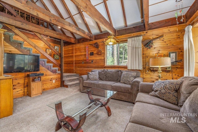 living area featuring vaulted ceiling with beams, wooden walls, carpet floors, and stairway
