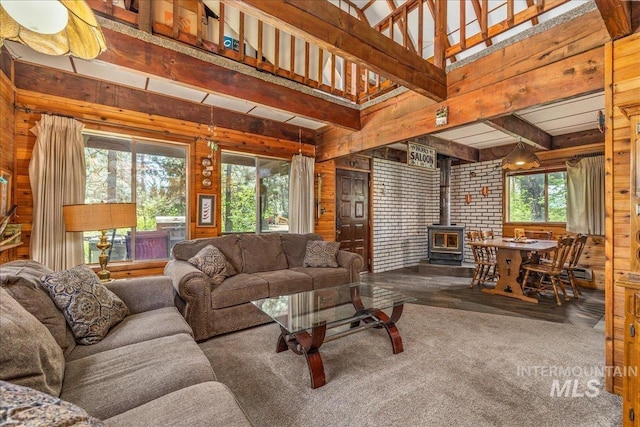 living room with wooden walls, a wood stove, and beam ceiling