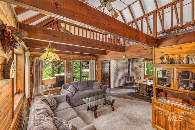living room with high vaulted ceiling, a wood stove, and wooden walls
