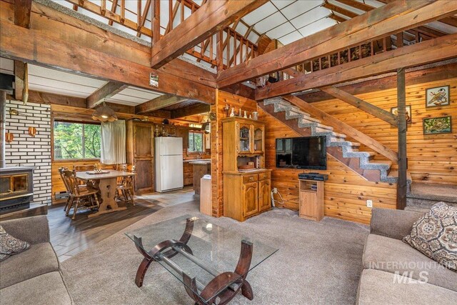 living room featuring stairway, wood walls, and lofted ceiling with beams