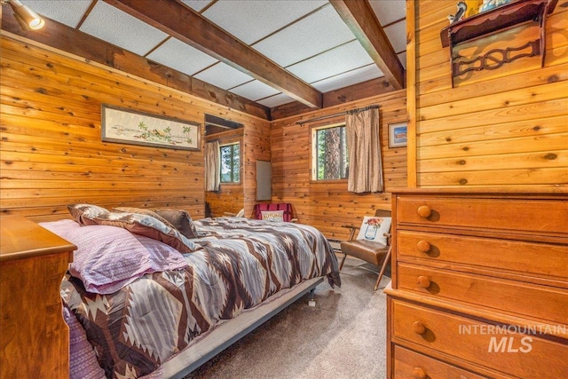 carpeted bedroom featuring beamed ceiling and wooden walls