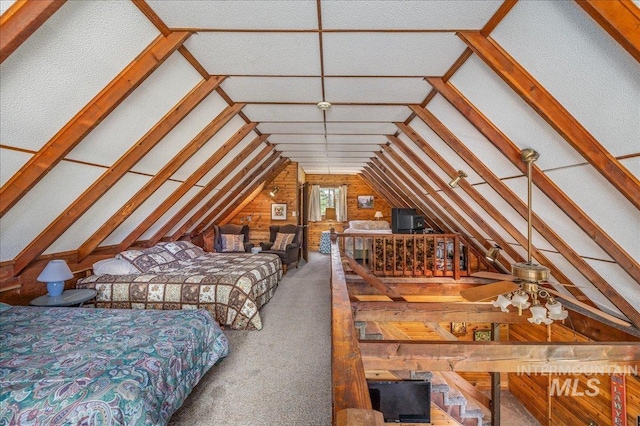 carpeted bedroom featuring vaulted ceiling and wooden walls