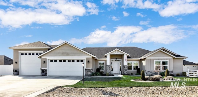 craftsman house with an attached garage, fence, stone siding, driveway, and a front lawn