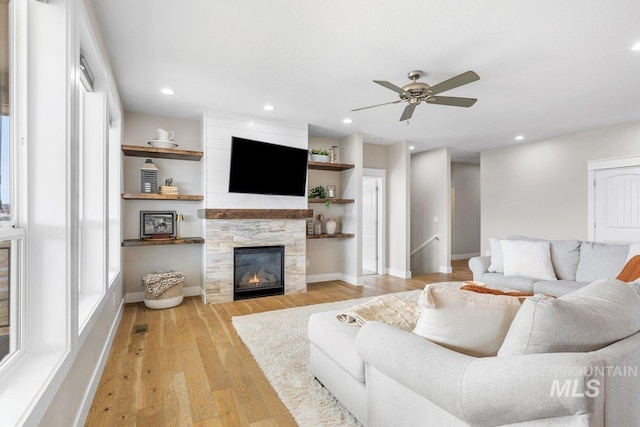 living room with light wood-type flooring, a glass covered fireplace, baseboards, and recessed lighting