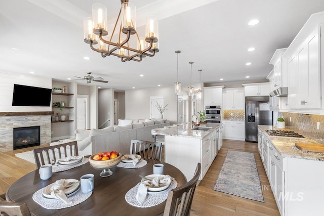 dining area featuring ceiling fan, a glass covered fireplace, light wood-style flooring, and recessed lighting