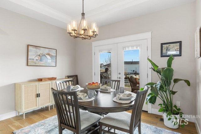 dining area featuring a notable chandelier, french doors, light wood finished floors, and baseboards