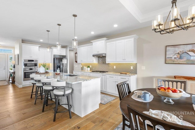 kitchen featuring stainless steel appliances, backsplash, a sink, and light wood-style floors