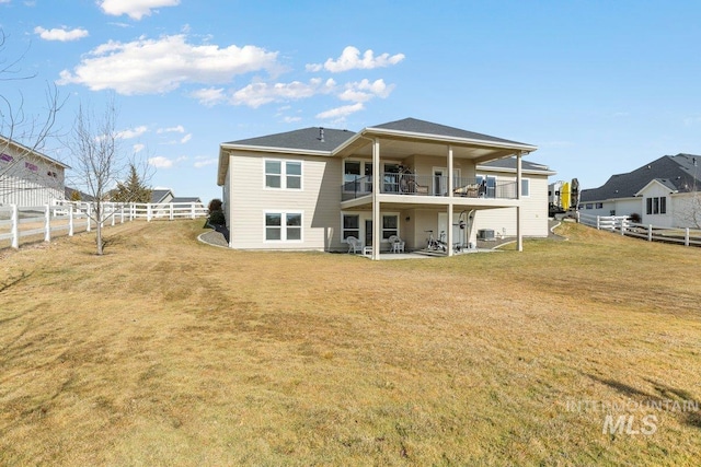 rear view of house featuring a fenced backyard, a yard, a balcony, and a patio