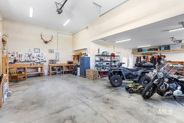 garage featuring a garage door opener, electric panel, and a workshop area