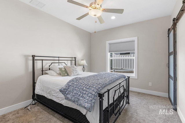 bedroom featuring light carpet, a barn door, visible vents, and baseboards