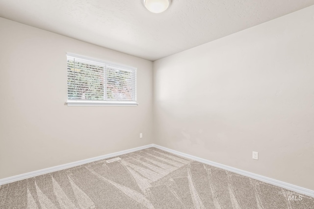 carpeted empty room featuring visible vents, a textured ceiling, and baseboards