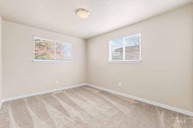 empty room featuring carpet and baseboards