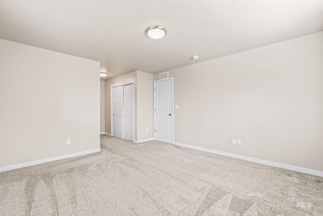 spare room featuring visible vents, light carpet, and baseboards