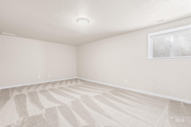 carpeted spare room with visible vents, a textured ceiling, and baseboards