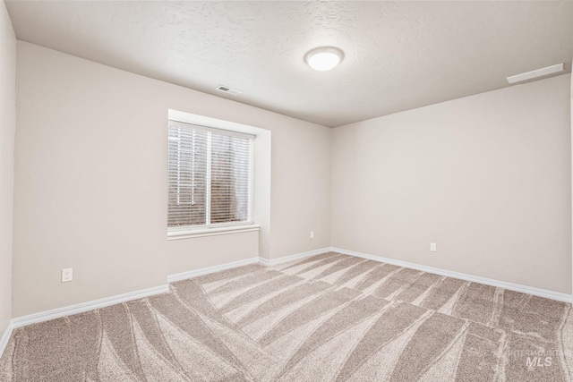 empty room with baseboards, visible vents, carpet floors, and a textured ceiling